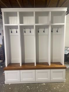 a room with some white cabinets and hooks on the doors, one shelf has two benches