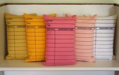 four pillows sitting on top of a shelf in front of a bookcase with numbers