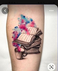 a tattoo with an open book and coffee cup on the left leg, watercolor splattered background