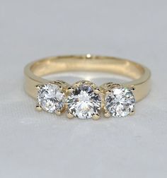 💙 14k solid gold three stone ring with D Color (colorless) moissanite gemstones as the best alternative for natural diamonds. 💙 Unique design ring for engagement, wedding, anniversary and milestones. 💙 Handcrafted with love and great care at San Francisco Bay! 💙 The ring material is 14k solid gold, should not be confused with gold plating or filling. It won't tarnish or fade over time. 💙 We're offering the finest quality and we gladly accept returns if you find our items less than perfect a Formal Moissanite Three Stone Rings, Yellow Gold Three Stone Diamond Promise Ring, Moissanite Three-stone Diamond Ring, Classic Three Stone Moissanite Wedding Ring, Round Three-stone Moissanite Diamond Ring, Moissanite Three Stone Diamond Ring, 14k Gold Three Stone Diamond Ring For Anniversary, Anniversary 14k Gold Three-stone Diamond Ring, 14k Gold Three-stone Diamond Ring For Anniversary