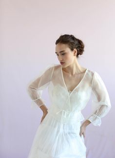 a woman in a white dress poses for the camera with her hands on her hips