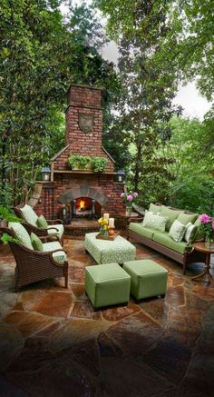 an outdoor living area with furniture and a fire place in the center, surrounded by greenery