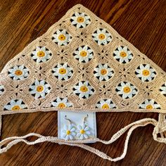 a crocheted purse with flowers on it sitting on a wooden table next to a cell phone