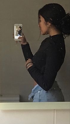 a woman standing in front of a mirror taking a selfie