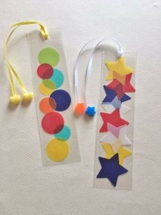 two bookmarks made out of colored paper and string with star shapes on them next to each other