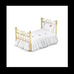 a doll bed with white sheets and pink flowers on the bottom, and gold metal headboard