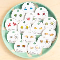 a green bowl filled with lots of different types of buttons on top of a wooden table