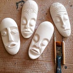 three white masks sitting on top of a table next to a paintbrush and an artist's palette