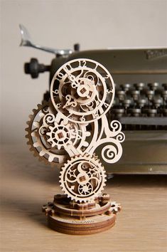 an intricately designed wooden clock sitting on top of a table next to a typewriter