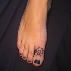 a woman's foot with a small sun tattoo on the top and bottom of it