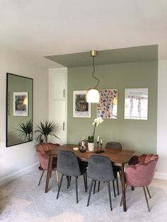 a dining room with green walls and pink chairs