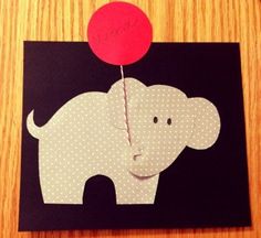 an elephant with a red balloon attached to it's back on top of a wooden table