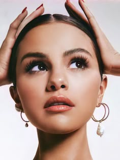 a woman with her hands on her head and eyes closed, wearing large hoop earrings