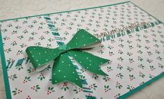 a close up of a card with a green bow on the front and white background