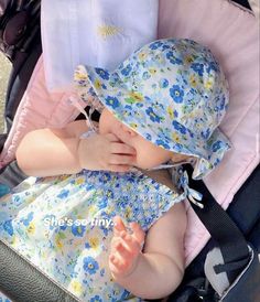 a baby is sitting in a stroller and wearing a blue flowered dress with matching hat