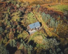 an aerial view of a house surrounded by trees in the middle of a grassy area