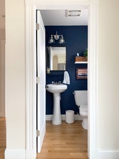 an open door leading to a bathroom with blue walls and white fixtures on the wall