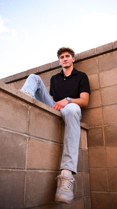 a young man sitting on top of a brick wall