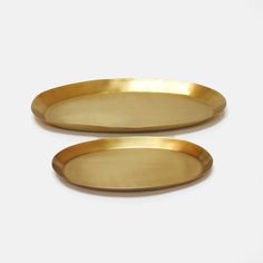 two gold oval trays sitting on top of each other