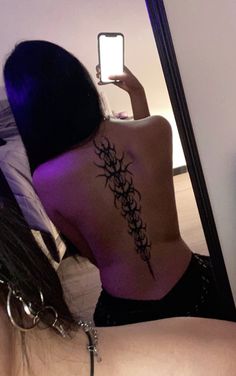 a woman with a tattoo on her back taking a selfie