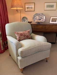 a living room with a chair, lamp and pictures on the wall