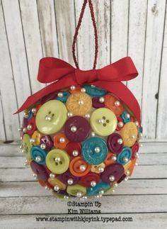 an ornament made out of buttons with a red ribbon