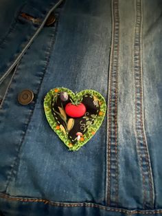 a heart shaped pin sitting in the back pocket of a jean jacket