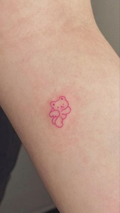 a small pink teddy bear tattoo on the left side of someone's right arm