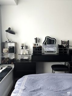 a black and white bedroom with a bed, desk, mirror and other items on it