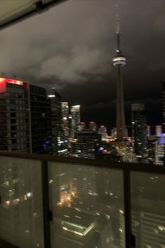 the city skyline is lit up at night with clouds in the sky and buildings on either side