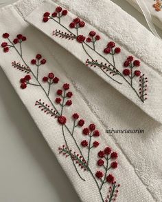 two white towels with red flowers and green stems on them, one is folded over the other