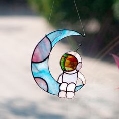 a stained glass sun catcher with a teddy bear on the moon hanging from it's side