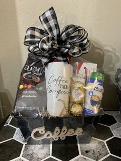 a gift basket with coffee and goodies in it on a tiled countertop next to a wall