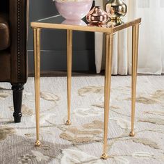 a gold side table with a bowl of flowers on it and a chair in the background