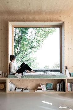 a person sitting on a window sill reading a book