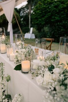 a long table with candles and flowers on it is set up for an outdoor wedding