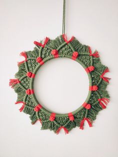 a green and red wreath hanging on the wall with pom - poms around it