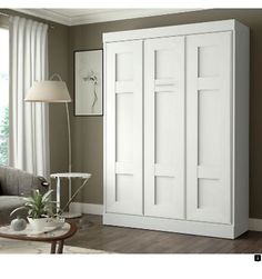 a living room filled with furniture and a white armoire next to a large window