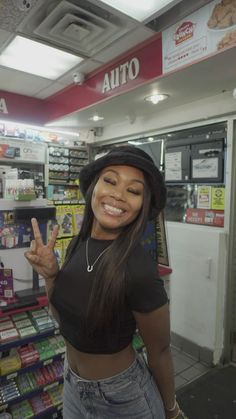 a woman standing in front of a store giving the peace sign with her hand and smiling