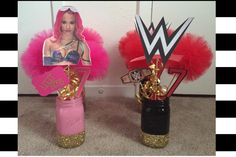 two vases decorated with pink and gold decorations, one has a female wrestler on it