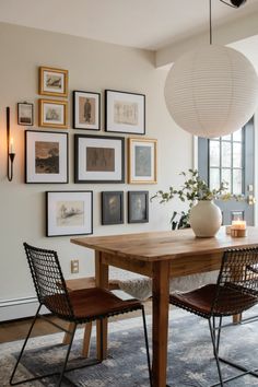 a dining room table with chairs and pictures on the wall above it in front of a window