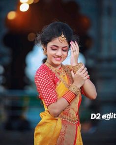 a woman in a yellow and red sari holding her hands together