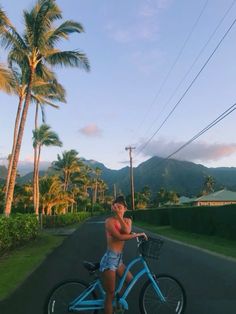 a man riding a blue bike down a street next to palm trees