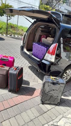 several pieces of luggage sitting on the ground next to a car with it's trunk open