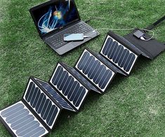 an open laptop computer sitting on top of a grass covered field next to solar panels