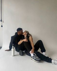 a man and woman are sitting on the floor with their arms around each other as they kiss