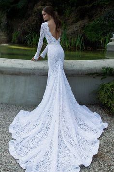 a woman in a white wedding dress standing by a fountain