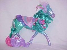 the toy horse is green and purple with pink flowers on it's back legs