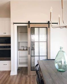 a dining room table with a vase on top of it next to an open kitchen door