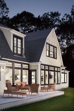 a large white house with lots of windows and furniture in the front yard at night